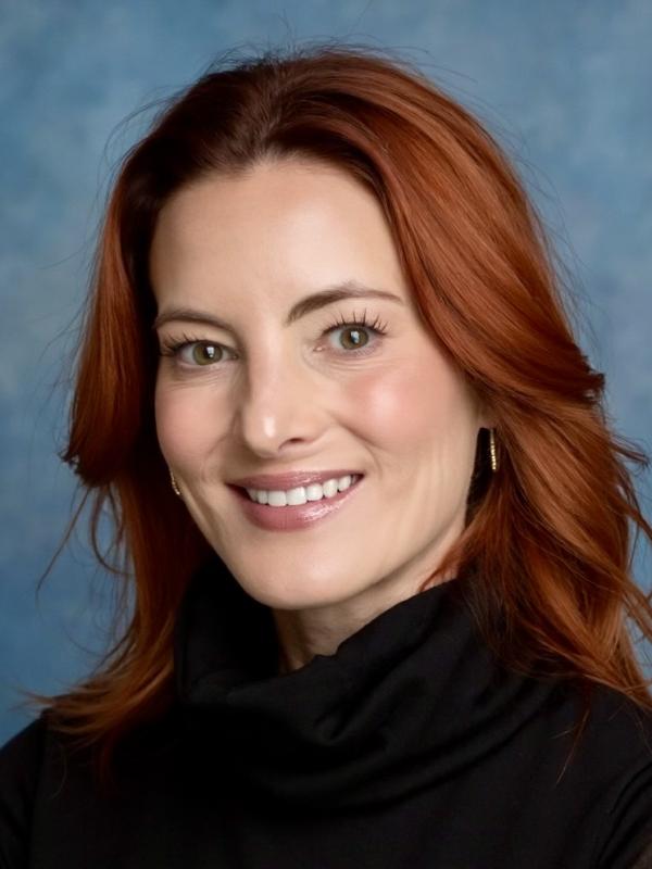 Picture of Lindsey smiling in front of a blue backdrop